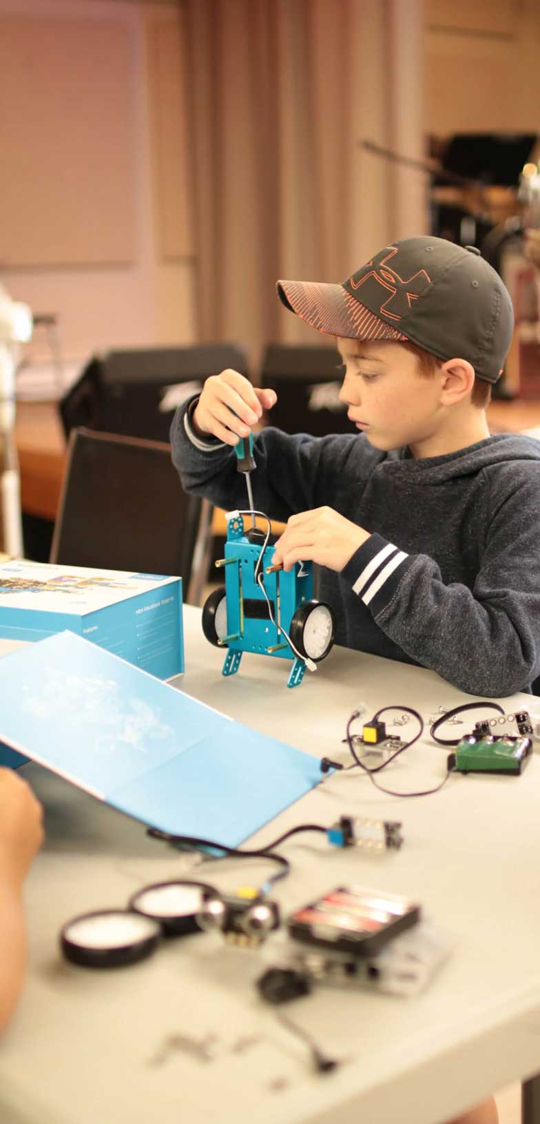 Young boy assembling an Mbot with a screw driver